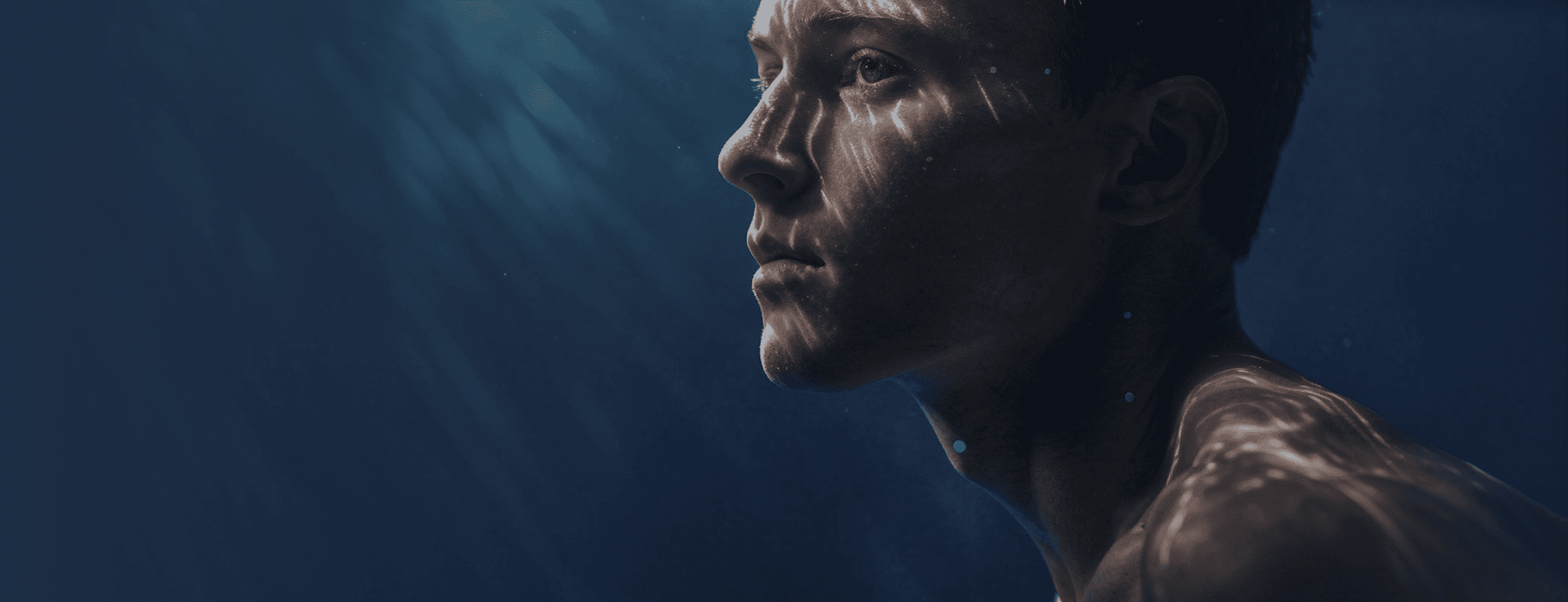 Young man floating underwater with sunlight rippling across his face